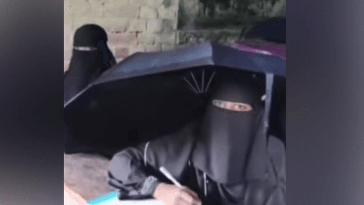Students write exams with umbrellas as rain leaks through roof in Patuakhali